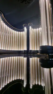 Golden light columns forming an arch, reflected on a dark surface