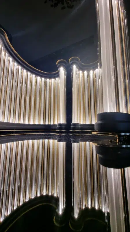 Golden light columns forming an arch, reflected on a dark surface