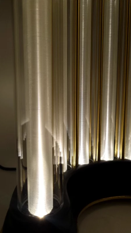 Close-up of golden and transparent light rods rising from the dark base of the Limen sculpture.
