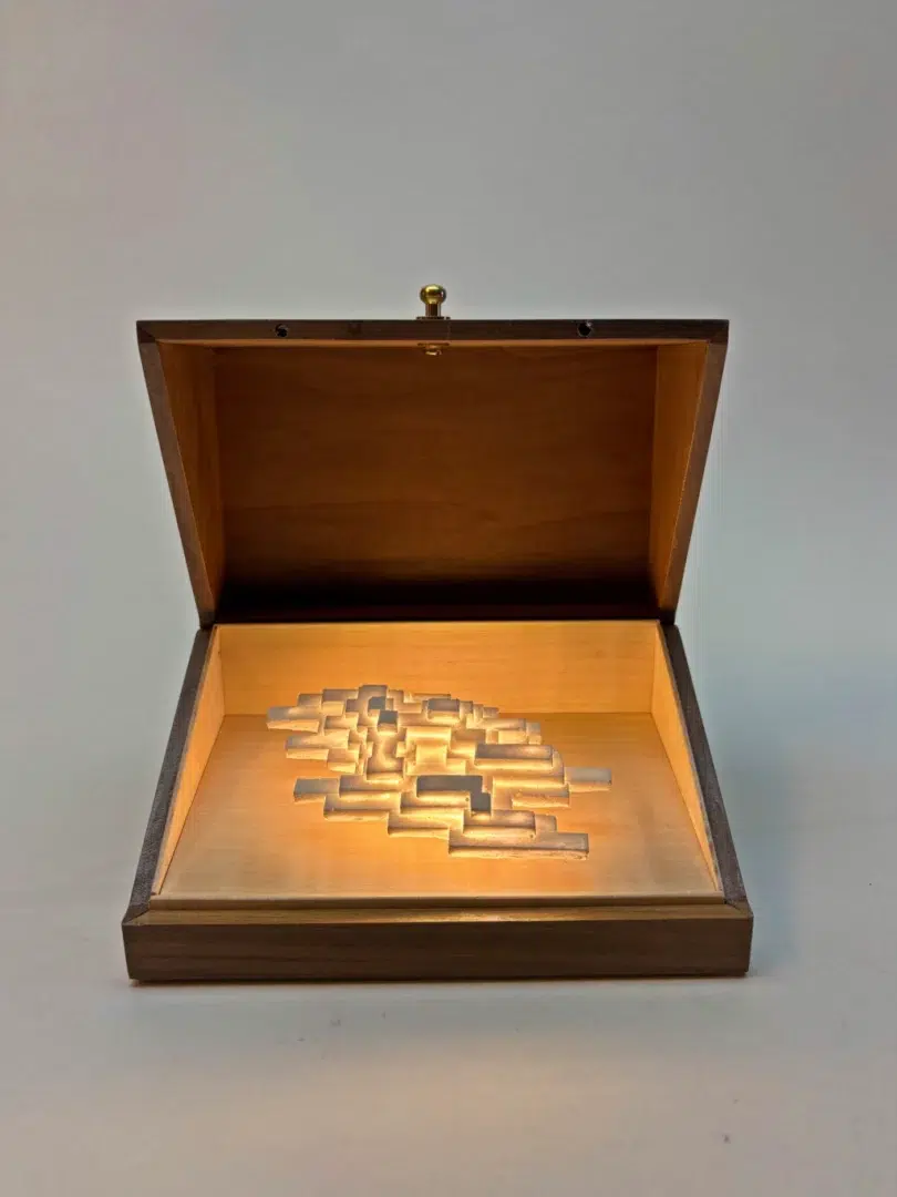 Open walnut box showing the white plaster sculpture of Vapor Minimus illuminated inside.