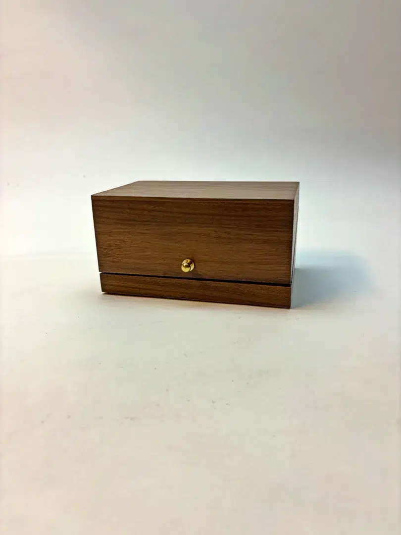 Closed walnut box of Vapor Minimus with golden clasp.