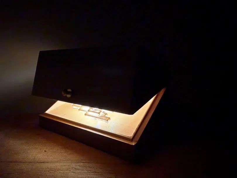 Vapor Minimus glowing inside an open walnut box in the dark.