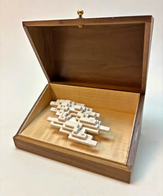 Open walnut box revealing the luminous white sculpture of Vapor Minimus, glowing like a fleeting vapor.