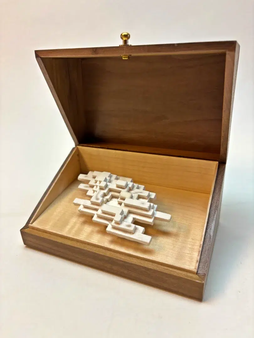 Open walnut box revealing the luminous white sculpture of Vapor Minimus, glowing like a fleeting vapor.