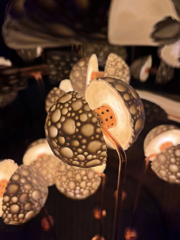 Close-up of the Germes de Lux Atlantis sculpture showing a luminous porcelain sphere with organic perforations and warm light filtering through.